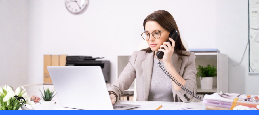 Secretária em clínica realizando atendimento telefônico e utilizando notebook, representando a automação de tarefas na rotina administrativa e no atendimento ao paciente.