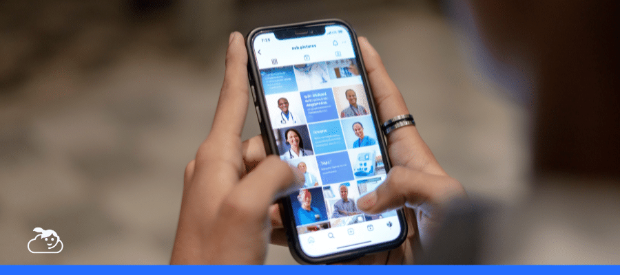 Foto em primeiro plano das mãos de uma pessoa segurando um smartphone e navegando por um perfil de clínica médica no Instagram. A tela mostra um feed organizado com fotos de profissionais de saúde e posts informativos. No canto inferior esquerdo, há o logotipo de uma nuvem sorridente (Cloudia). A imagem simboliza o momento em que um paciente descobre o perfil e inicia a interação que será gerenciada por um chatbot no Instagram, facilitando o acesso imediato a informações e agendamentos.