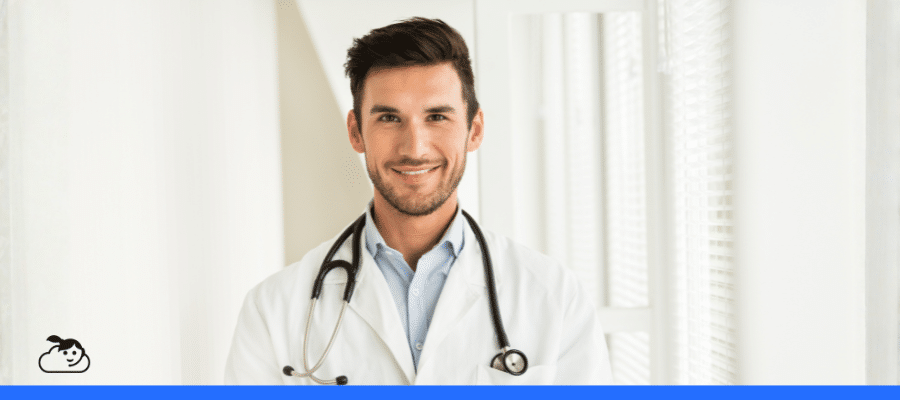 Close-up de um médico jovem, barbado, sorrindo e usando jaleco e estetoscópio, transmitindo profissionalismo e confiança essenciais para o marketing para clínicas e a atração de pacientes.