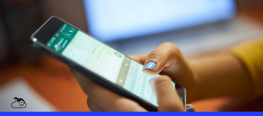 Mãos femininas digitando em um smartphone com o aplicativo WhatsApp aberto, simbolizando a realização de triagem de pacientes no WhatsApp em um ambiente de consultório ou escritório.