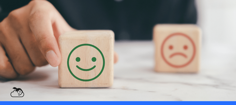 Mão segurando bloco de madeira com rosto sorridente representando avaliação positiva do NPS na saúde e a experiência do paciente.